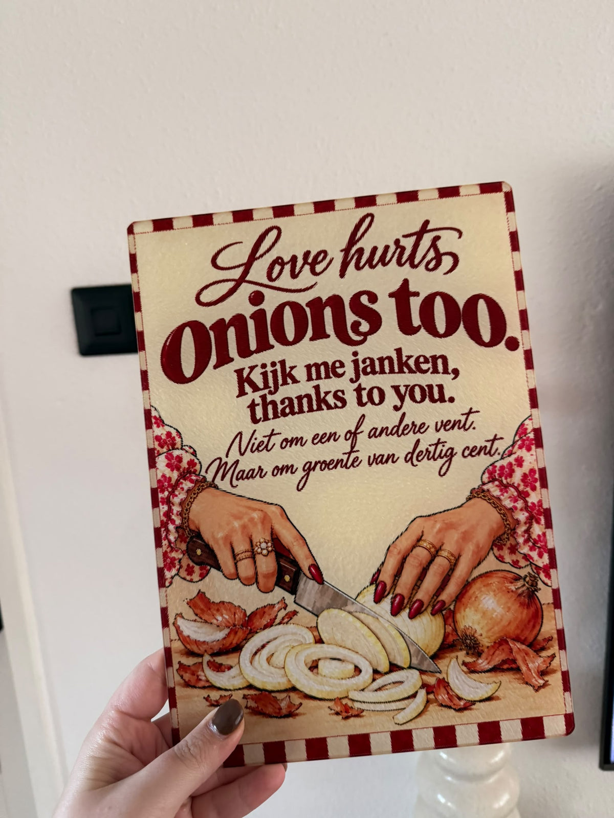 Glazen snijplank met rood geblokte rand, uienillustratie en tekst Love hurts, onions too