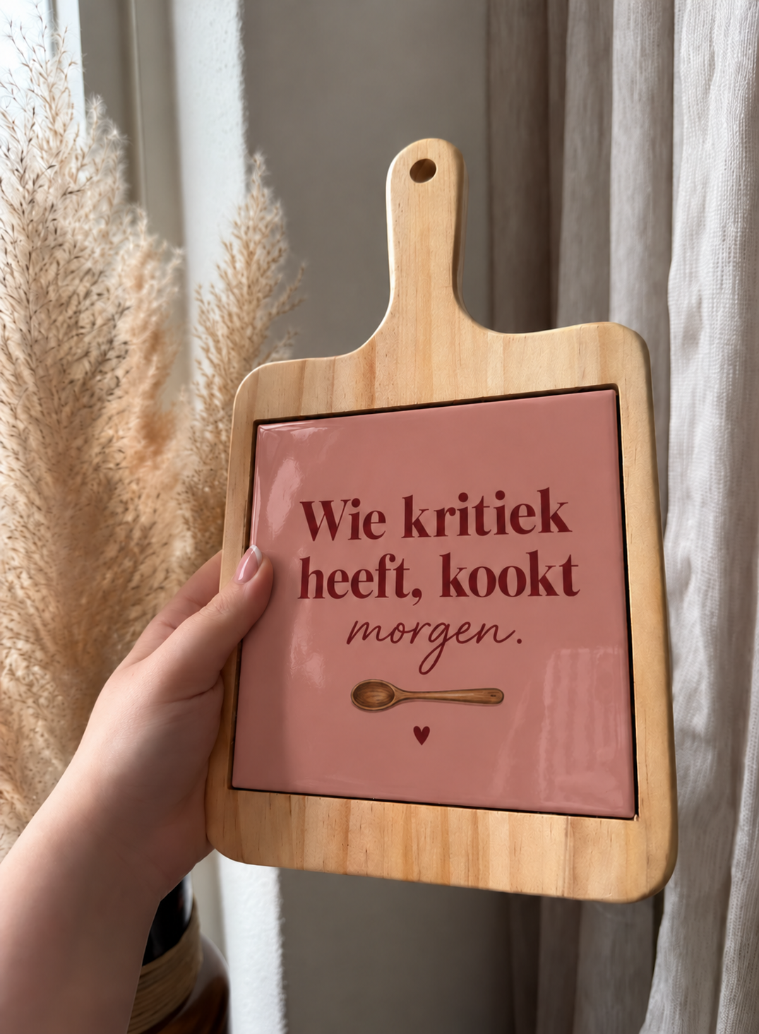 Houten borrelplank met handvat en een roze hoogglans keramische tegel met de tekst 'Wie kritiek heeft, kookt morgen.'